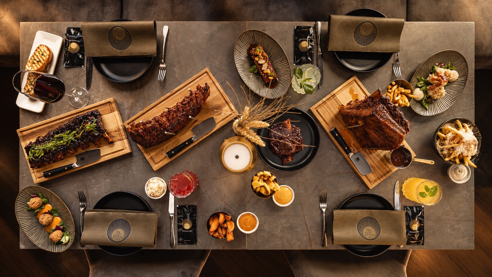 Von oben fotografierter, festlich gedeckter Tisch im St.Ribs mit Ribs-Boards, Beilagen, Drinks und Servietten mit St.Ribs-Logo